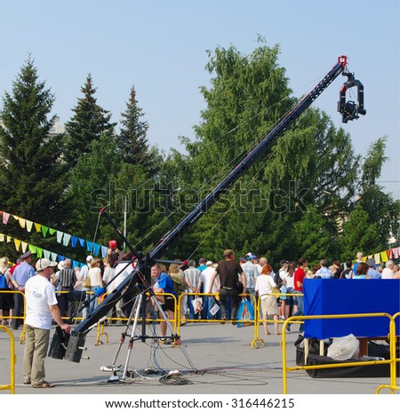 OMSK, RUSSIA  - AUGUST 07, 2010: Cameraman oeprates of camera on rod, shoots telereporting at public event