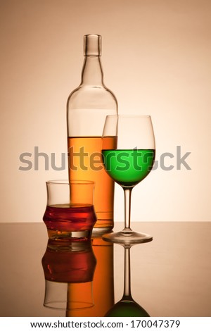 Still life composition with glasses and bottle filled with colored liquids