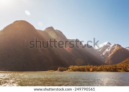 Majestic snow capped peaks of Milford Sound with sun flare. Fiordland, New Zealand