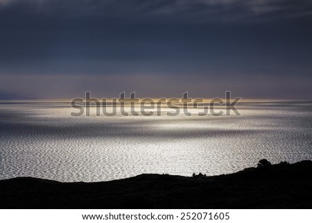 Smooth water surface with light and shadow play at sunset, Bluff Hill lookout, New Zealand.