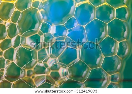Soap suds extreme closeup creating honeycomb pattern of golden lines