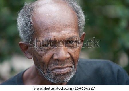 Old african american homeless man outdoors with sad eyes.
