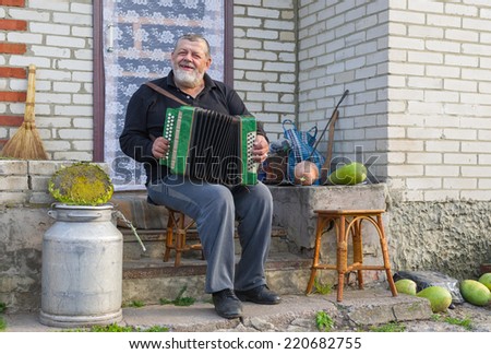 Ukrainian country-man playing button accordion (garmon) at the doorway