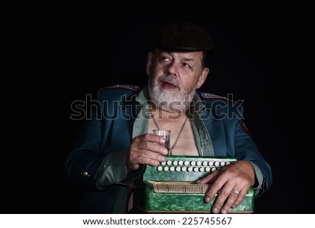 Portrait (low key) of an old retired military man who plays accordion for food and alcohol