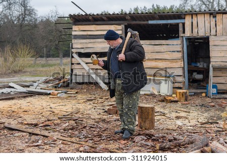 Full body portrait of old Ukrainian peasant with an axe