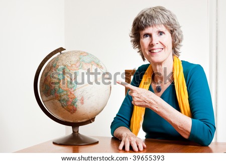 Senior lady pointing and smiling at a map / globe of planet earth