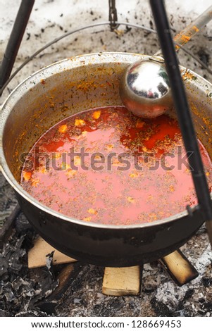 Traditional hungarian dish - bogracs goulash, stewed meat and vegetables in cauldron, outside in winter fireplace