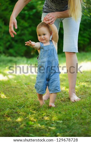 First steps of baby from mother on grass