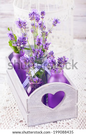 Lavender in bottles, decor provance style, wooden box and birdcage on crochet tablecloth