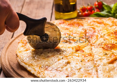 Pizza Margarita on the wooden board and pizza cutter