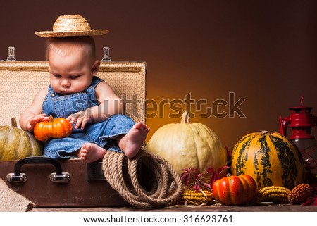 Cute baby posing on the background of pumpkins. Thanksgiving greetings