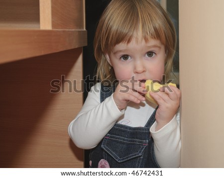 Little girl eat near the table. She hided and was surprised for you finded he