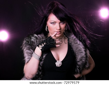 Woman in fur coat on black backgound and magenta light