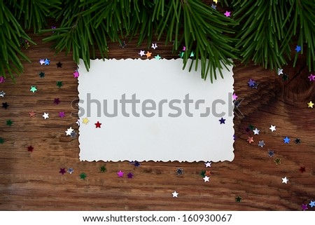 Christmas card: empty paper form with fir-tree branches and confettion old wooden background