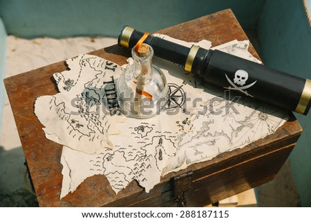 pieces of pirates map on the box with bottle and telescope