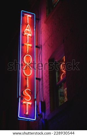 Neon lit sign tattooist on the wall of building in Soho, London