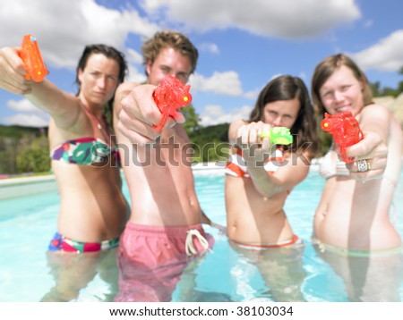friends playing with water guns in pool