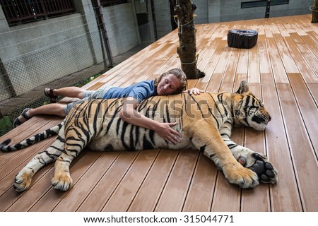Young man hugging a big tiger in Thailand