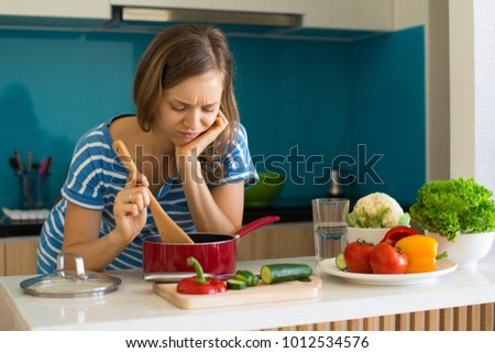 Dissatisfied Woman Cooking and Looking into Pan Stock foto © 