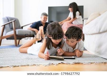 Similar – Image, Stock Photo Cute child lying on carpet at home and playing on console