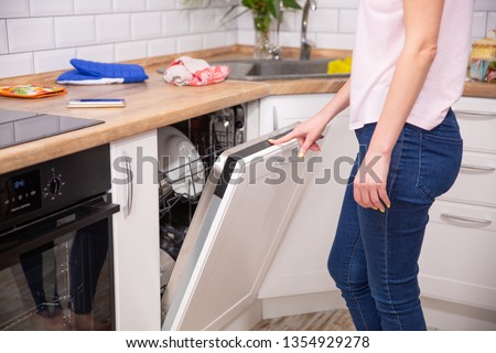 Washing dishes in the dishwasher. The woman puts dirty dishes in the dishwasher. Opening and closing the dishwasher.