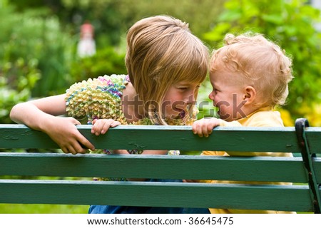 young brother and sister on a park bench