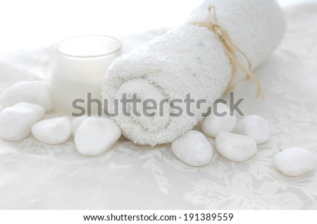 White towels with white stones and candle on lace