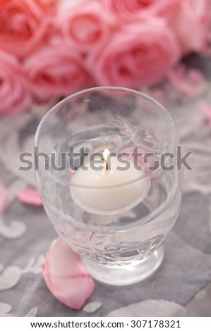 Pink rose petals and rose with candle on lace