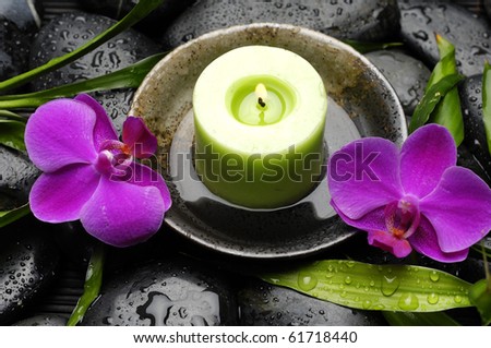 Wooden bowl of green candle with pink orchid bamboo leaves