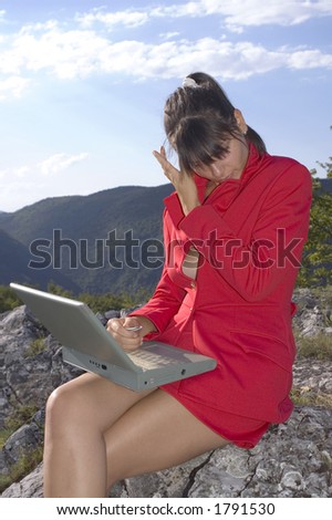 Business woman in red clothes with laptop at top of mountains