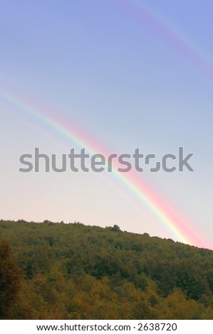 Rainbow at summer day after rain above mountain