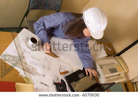 Woman engineer with helmet on head and arch project at table