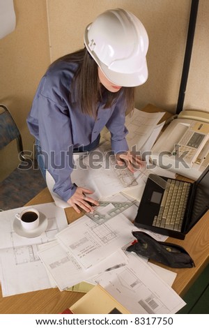 Female architect with helmet on head and arch project at table