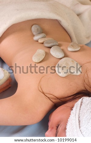 Young woman with a hot stone on back for treatment at a spa