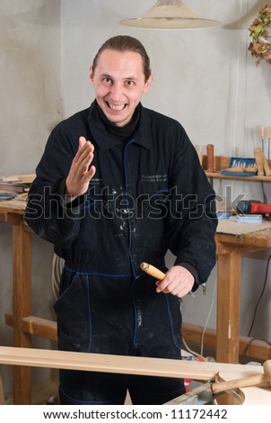 Young happy carpenter working in his workshop