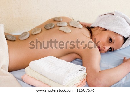 Young woman with a hot stone on back for treatment at a spa