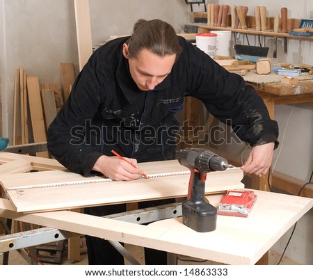 Young carpenter making measure with meter in workshop