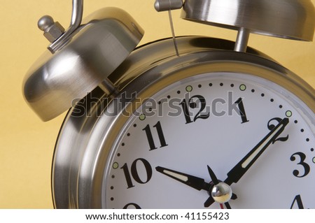 Macro of Retro Silver Alarm Clock Isolated on a Yellow Background.