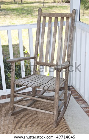 Worn wooden rocking chair on a screened in porch.
