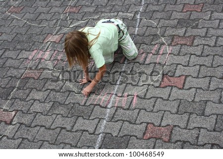 a girl in the street painting with chalk