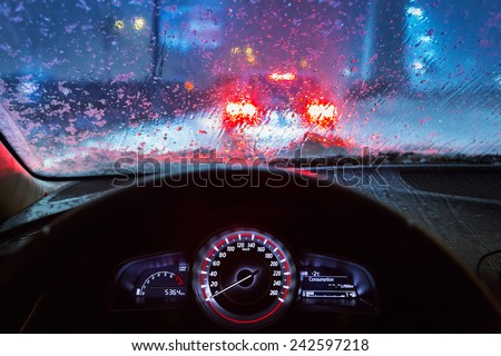 Blurry car silhouette seen through snowy and wet windscreen