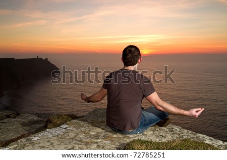 Man at meditation on Cliffs of Moher at sunset