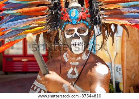TULUM, MEXICO - JULY 15: Unknown man in Mayan traditional ornamental feather headdress playing on drums to the ritual pleased the rain god Xipe Totec. July 15, 2011 in Tulum, Quintana Roo, Mexico