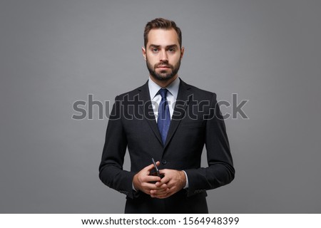 Serious young bearded business man in classic suit shirt tie posing isolated on grey background studio portrait. Achievement career wealth business concept. Mock up copy space. Holding mobile phone ストックフォト © 