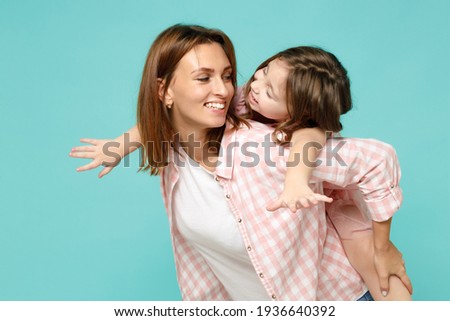 Happy woman in pink clothes have fun with child baby girl 5-6 years old Mommy little kid daughter stand behind hug kiss isolated on pastel blue azure background studio Mother's Day love family concept