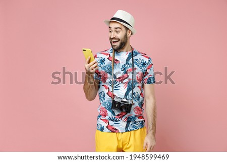 Excited young traveler tourist man in summer clothes, hat using mobile cell phone typing sms message isolated on pink background. Passenger traveling abroad on weekends. Air flight journey concept ストックフォト © 