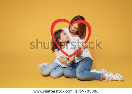 Full body length happy woman in basic white t-shirt have fun sit on floor child baby girl 5-6 years old Mom mum little kid daughter isolated on yellow color background studio Mother's Day love family