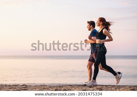 Full body profile couple young two friends strong sporty sportswoman sportsman woman man 20s in sport clothes warm up training run on sand sea ocean beach outdoor jog on seaside in summer day morning Foto stock © 