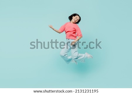 Full body young smiling singer happy woman of Asian ethnicity 20s in pink sweater jump high paly guitar isolated on pastel plain light blue color background studio portrait. People lifestyle concept Stock fotó © 