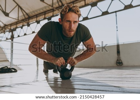 Full size young strong sporty athletic toned fit sportsman man 20s in sports clothes warm up training work out engaged with kettlebell at outdoor gym sea beach outdoor seaside in summer day morning. Foto stock © 